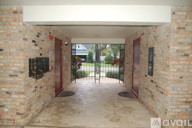 A brick archway leads to a gate and a green lawn.