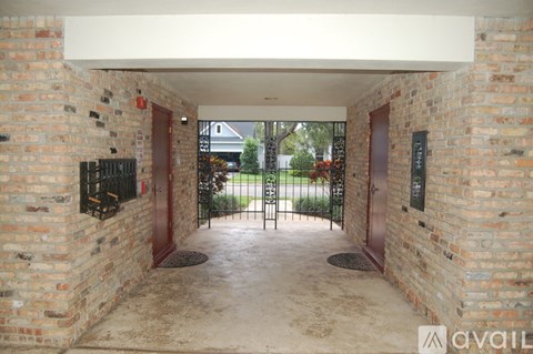 A brick archway leads to a gate and a green lawn.