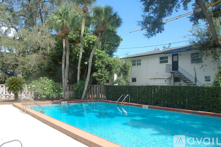 A swimming pool surrounded by trees and a house in the background.