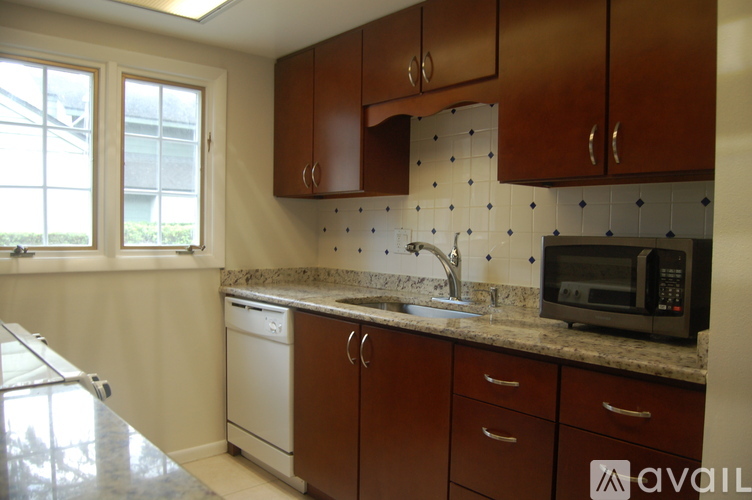 A kitchen with brown cabinets and a black microwave.