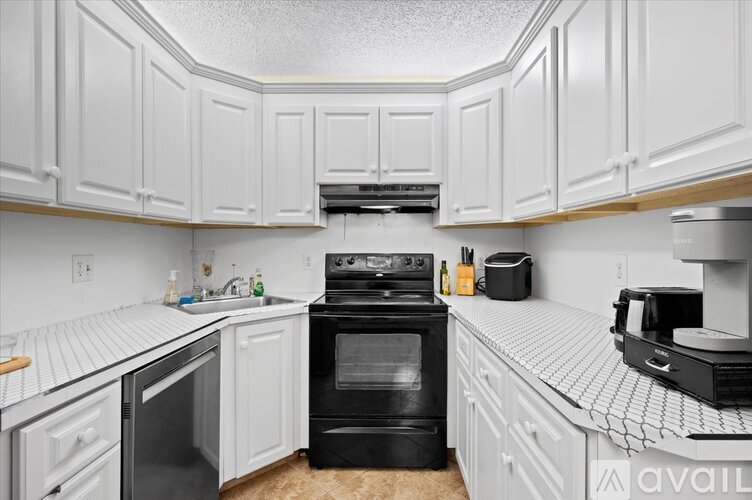 A kitchen with white cabinets and black appliances.