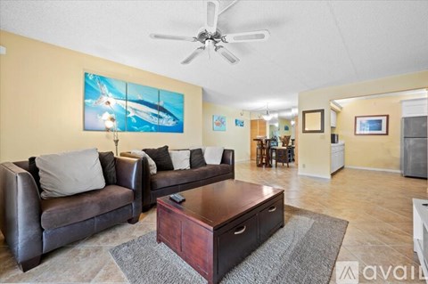 A living room with a brown leather couch, a coffee table, and a painting on the wall.