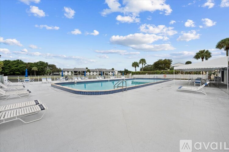 A large outdoor swimming pool with loungers and a clear blue sky.