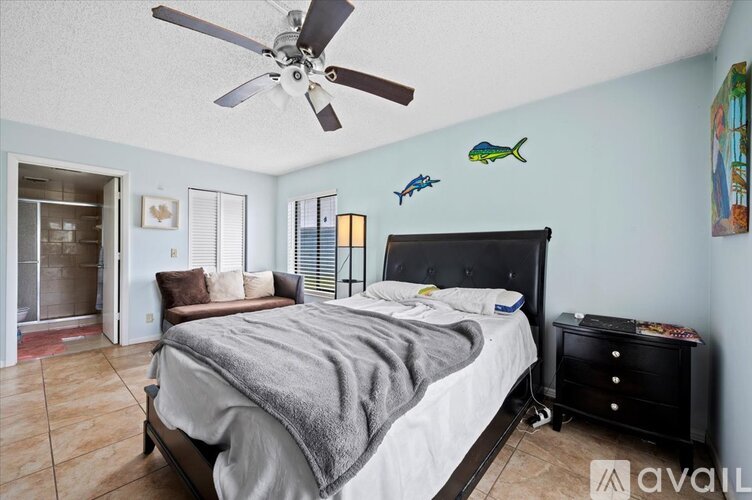 A bedroom with a bed, dresser, and ceiling fan.