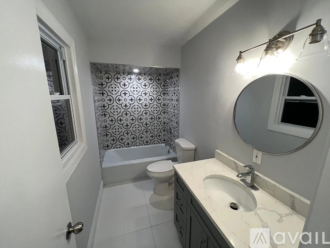 A bathroom with a toilet, sink, and a mirror.