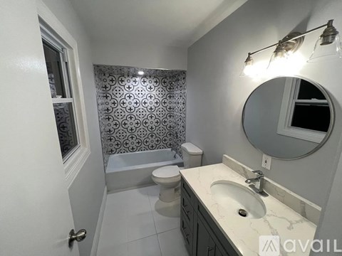 A bathroom with a toilet, sink, and a mirror.