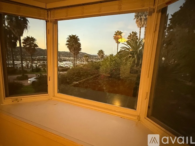A window with a view of palm trees and a hilly landscape.