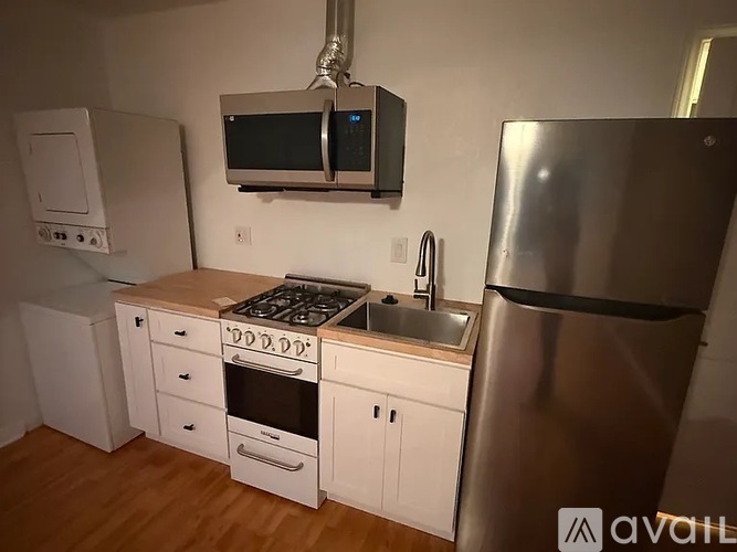 A kitchen with a stove, sink, and refrigerator.