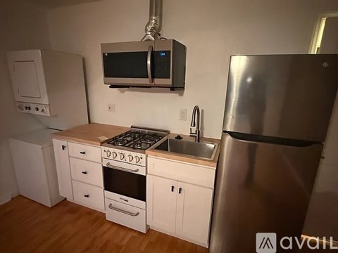 A kitchen with a stove, sink, and refrigerator.