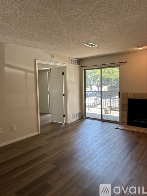 A room with wooden floors and a sliding glass door leading to a balcony.