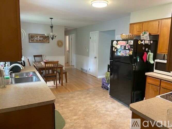 A kitchen with a black fridge and wooden cabinets.
