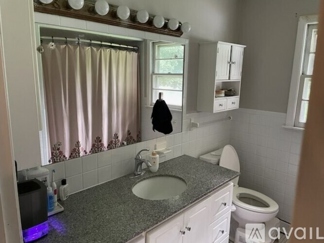 A bathroom with a sink, toilet, and a window with a curtain.