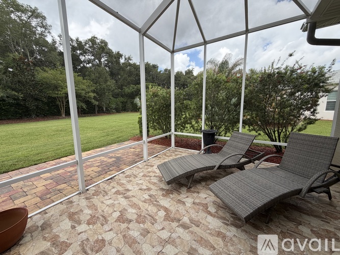 A patio with a glass roof, grey chairs and a brick floor.