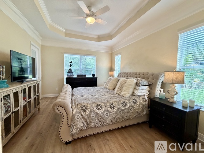 A bedroom with a large bed and a television on the wall.