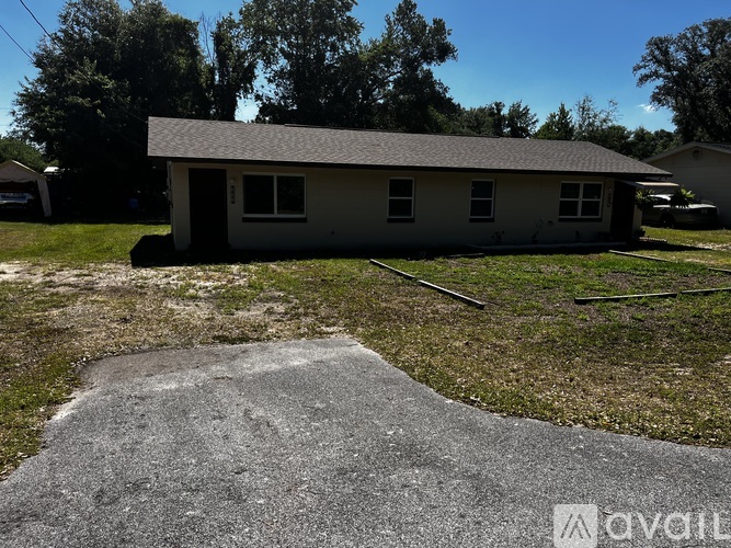 A house with a grey roof and a concrete pathway in front.