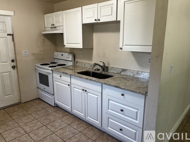 A kitchen with white cabinets and a marble countertop.