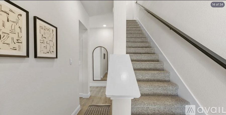 A hallway with a staircase and two framed pictures on the wall.