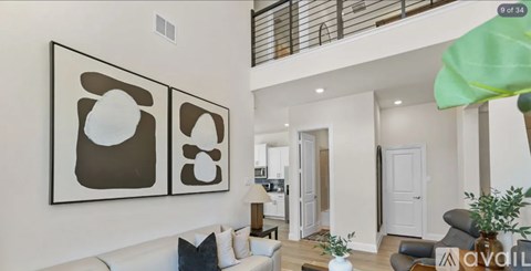 A living room with a white couch and two abstract paintings on the wall.