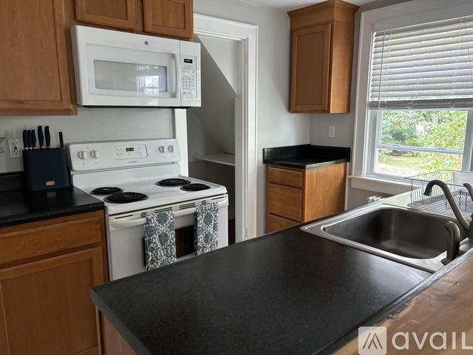 A kitchen with a white stove and black countertops.