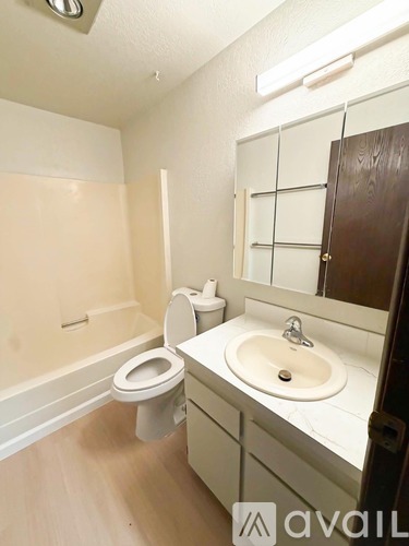 A bathroom with a toilet, sink, and mirror.