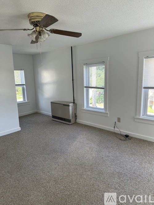 A room with a ceiling fan and carpeted floor.