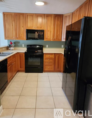 A kitchen with wooden cabinets and black appliances.