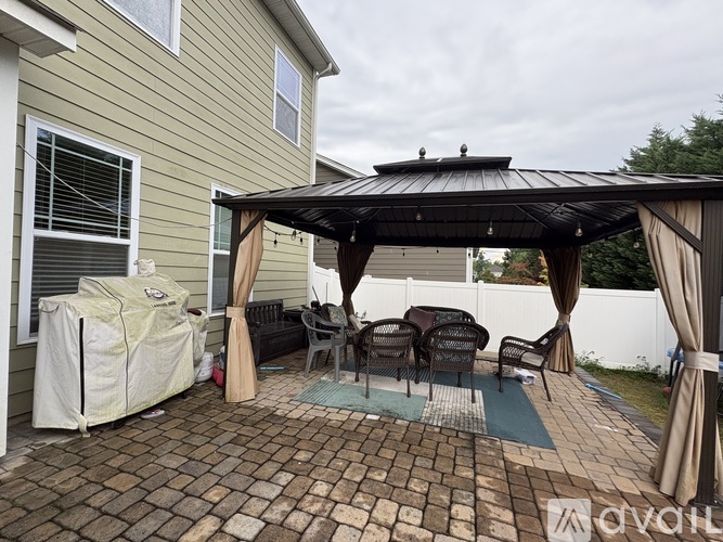 A patio with a black canopy and chairs under it.