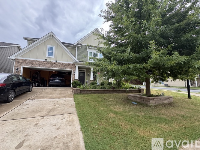 A house with a garage and a tree in front.