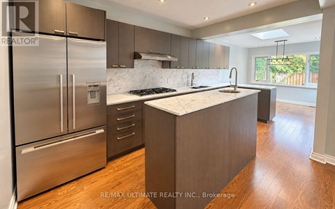 A modern kitchen with stainless steel appliances and wooden flooring.