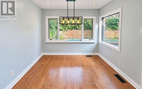 A room with wooden floors and a large window with a view of a fence.
