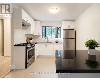 A modern kitchen with white cabinets and black countertops.