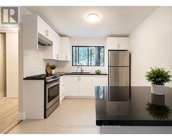 A modern kitchen with white cabinets and black countertops.