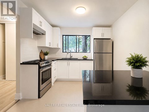 A modern kitchen with white cabinets and black countertops.