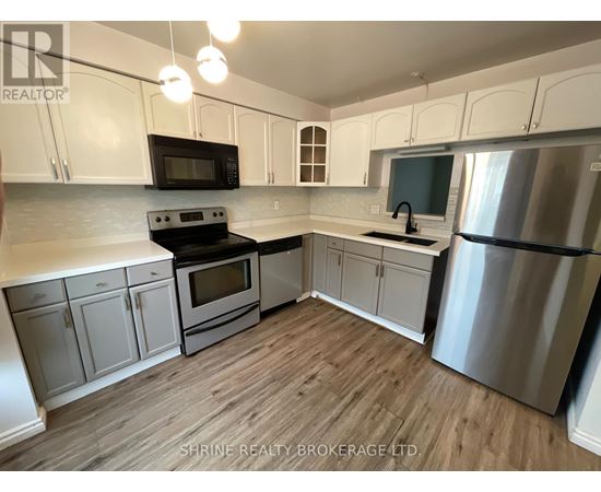 A kitchen with white cabinets and a wooden floor.