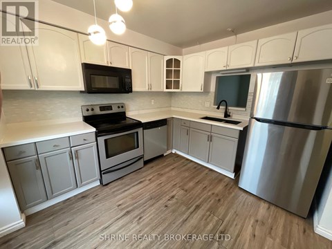 A kitchen with white cabinets and a wooden floor.
