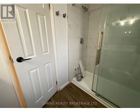 A white door with a black handle is in a bathroom with a glass shower stall.