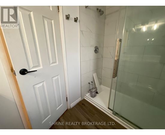 A white door with a black handle is in a bathroom with a glass shower stall.