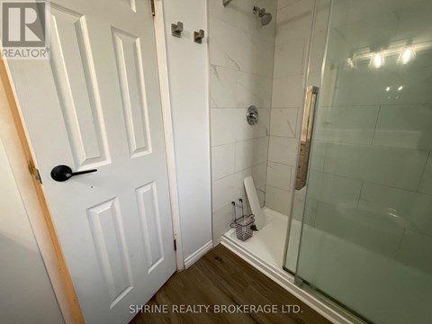 A white door with a black handle is in a bathroom with a glass shower stall.
