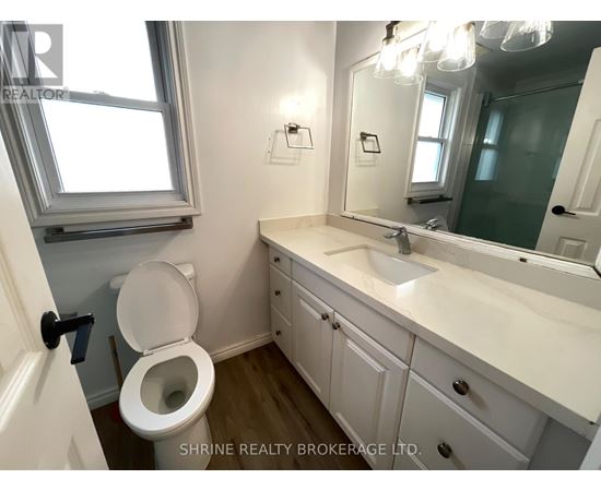 A white bathroom with a toilet, sink, and mirror.