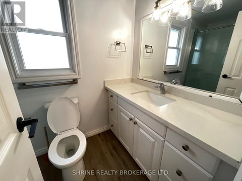 A white bathroom with a toilet, sink, and mirror.