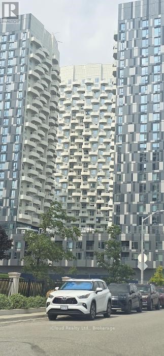 A white car is driving down a street lined with tall buildings.
