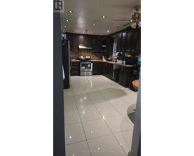 A kitchen with white tile flooring and dark wood cabinets.