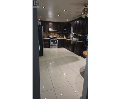 A kitchen with white tile flooring and dark wood cabinets.