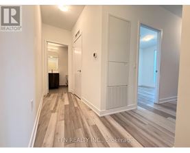 A hallway with wood flooring and white walls.