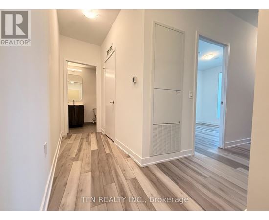 A hallway with wood flooring and white walls.
