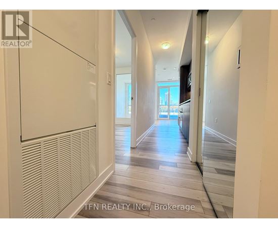 A hallway with a white wall and a wooden floor.