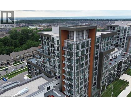 A modern multi-story building with a glass facade and a parking lot in front.