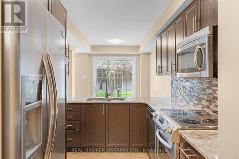 A kitchen with a stainless steel refrigerator and wooden cabinets.