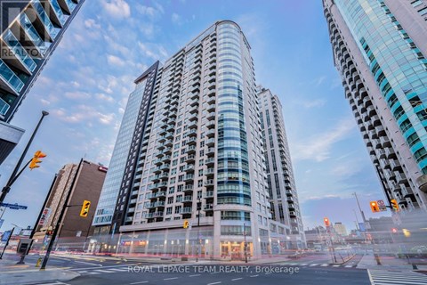 A modern building with a curved glass facade stands in the foreground of a city street.