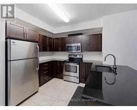 A kitchen with a refrigerator, microwave, oven, and sink.
